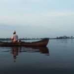 Kerala A man paddling a canoe on the serene Alappuzha backwaters at dawn, India.