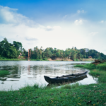 Kerala Tranquil riverside scene featuring a traditional boat and lush greenery in Ramamangalam, Kerala.